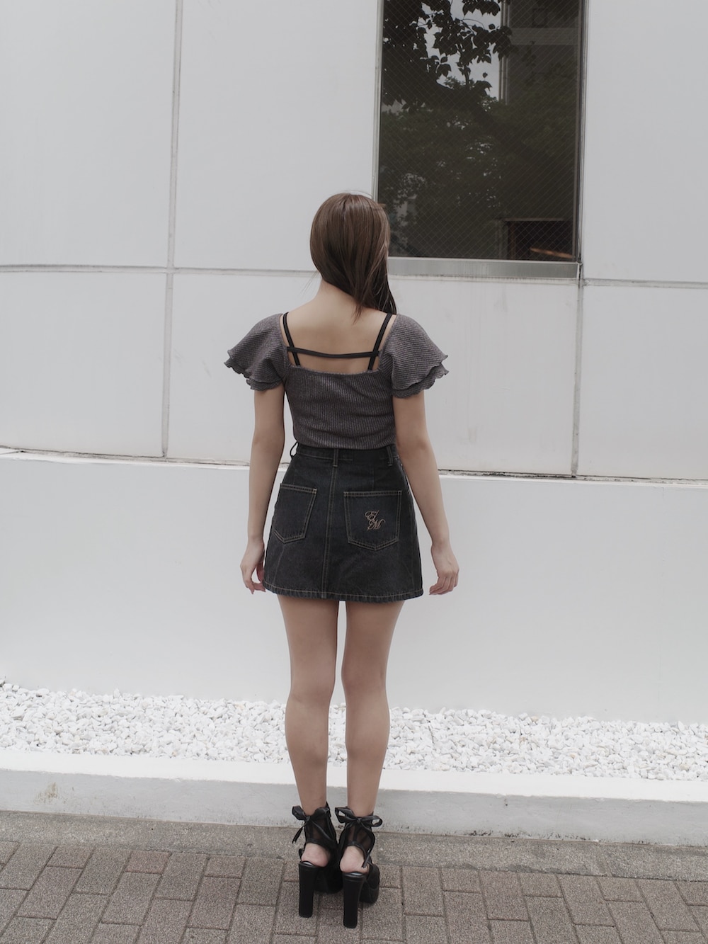 ブラック系のデニムスカート、ブラック系のサンダル、グレー系のTシャツ/カットソーを着用したレディースの夏コーディネートの5枚目の写真