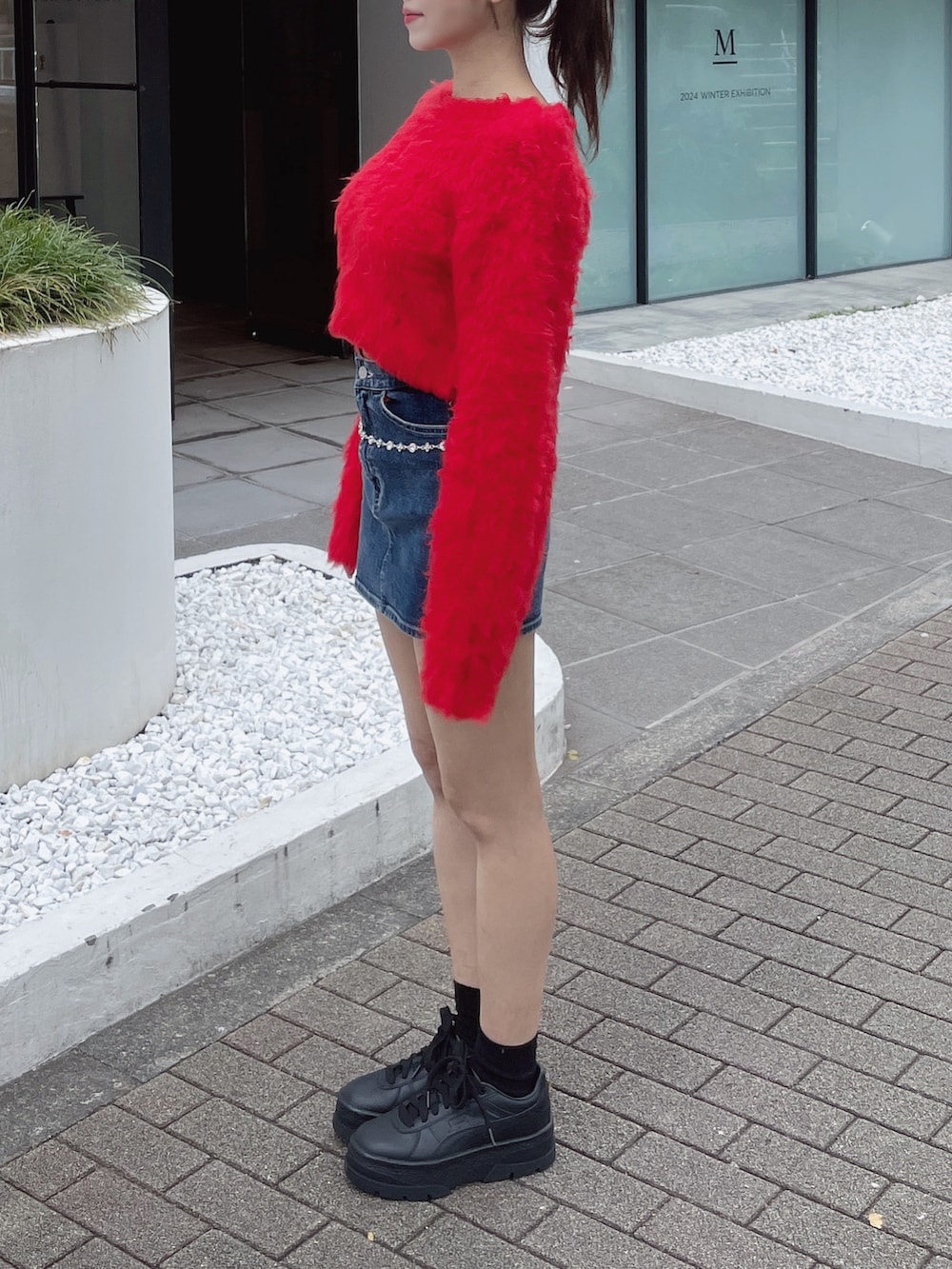 レッド系のニット/セーター、ホワイト系のスニーカー、ブルー系のデニムスカートを着用したレディースの秋コーディネートの5枚目の写真