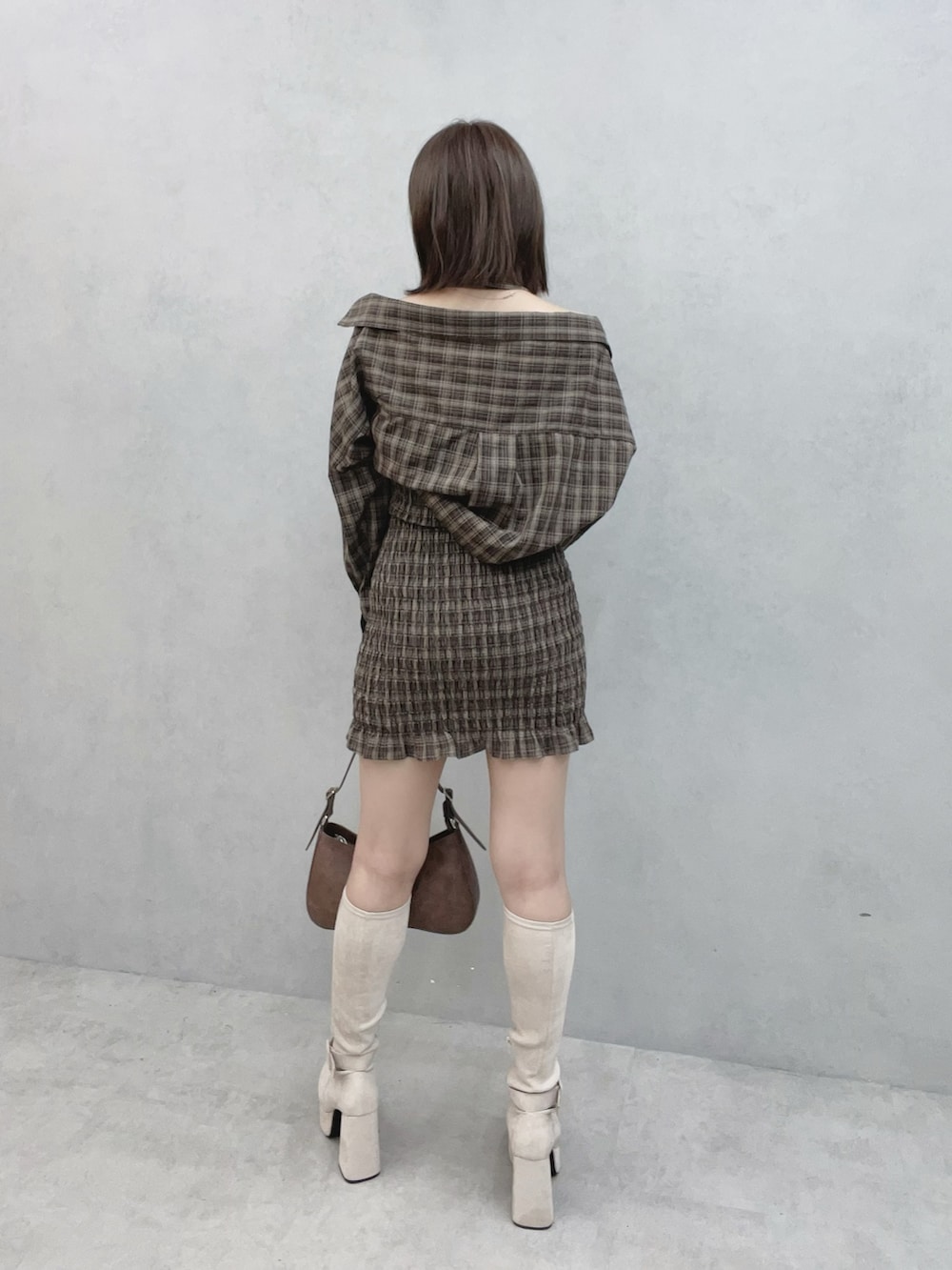 ブラウン系のワンピース、ブラウン系のショルダーバッグ、ホワイト系のブーツを着用したレディースの秋コーディネートの4枚目の写真