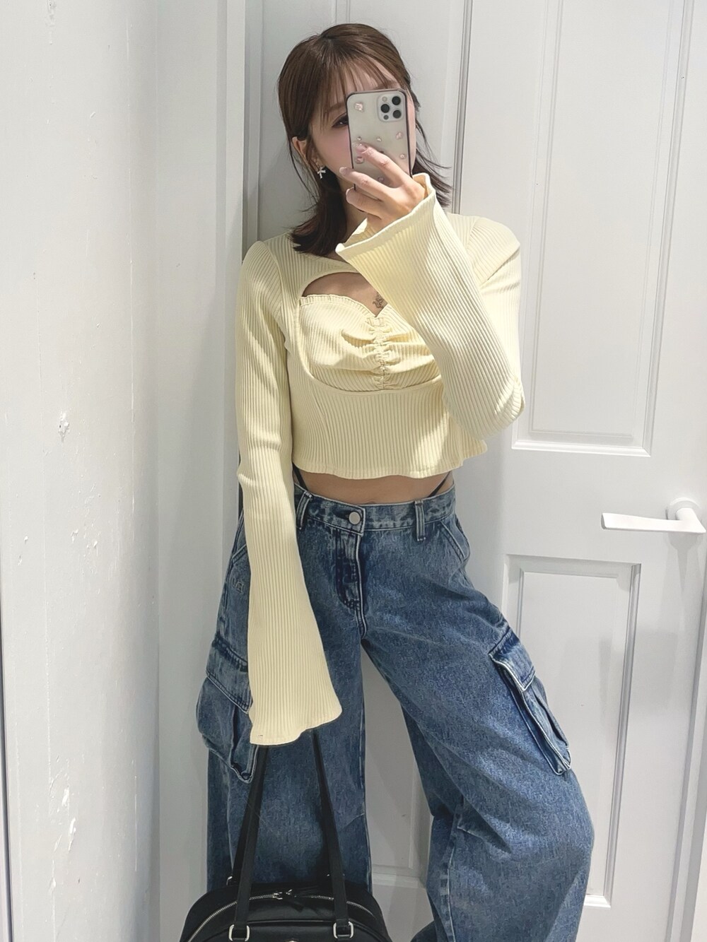 イエロー系のTシャツ/カットソー、ブルー系のデニムパンツ、ブラック系のボストンバッグを着用したレディースの冬コーディネートの2枚目の写真