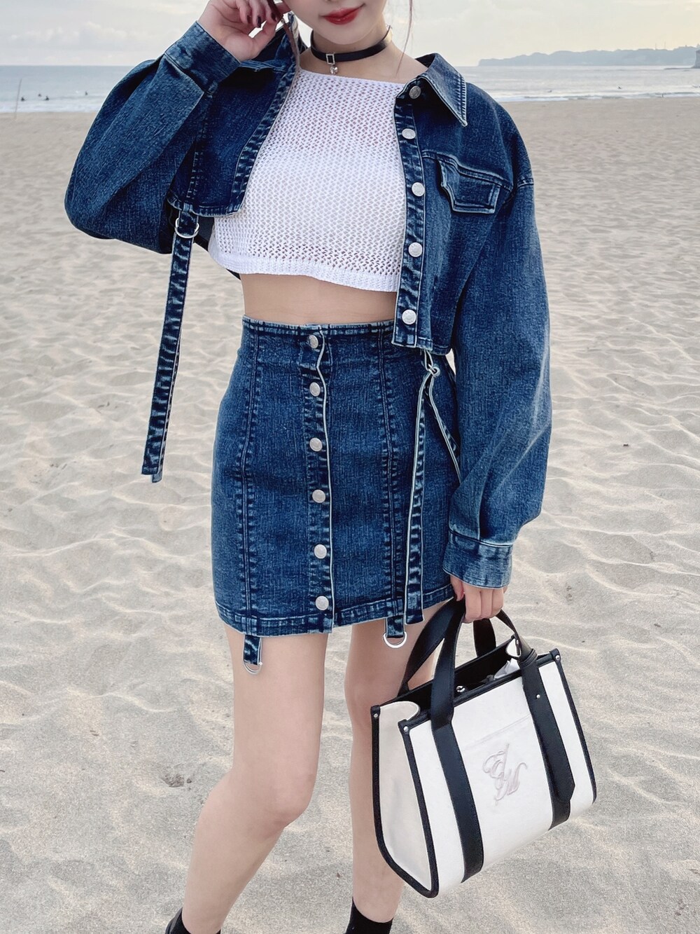 ブルー系のデニムジャケット、ブルー系のデニムスカート、ホワイト系のショルダーバッグを着用したレディースの冬コーディネートの2枚目の写真