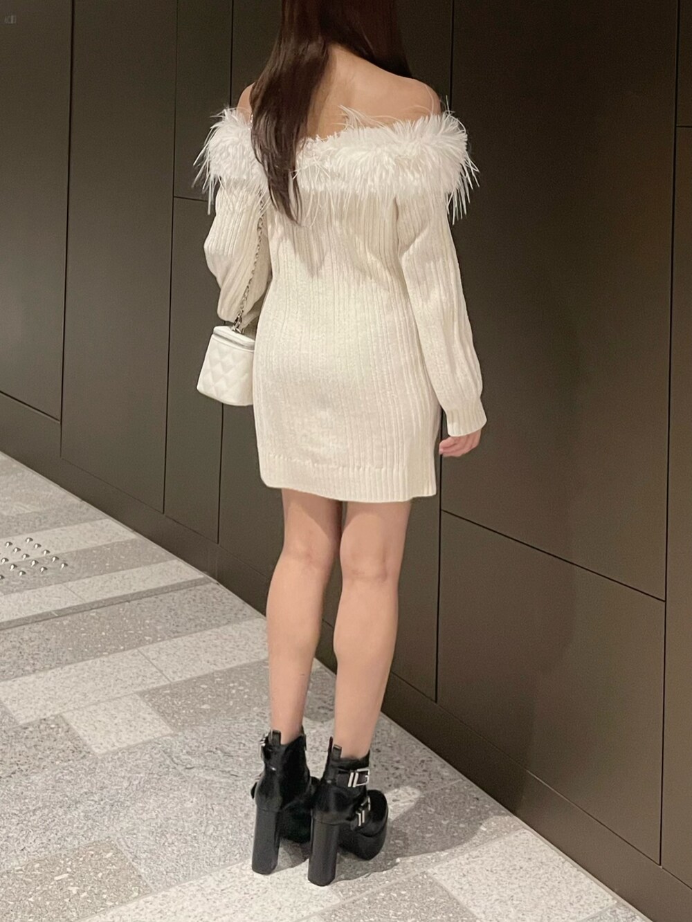 ホワイト系のワンピース、ホワイト系のハンドバッグ、ブラック系のブーツを着用したレディースの冬コーディネートの4枚目の写真