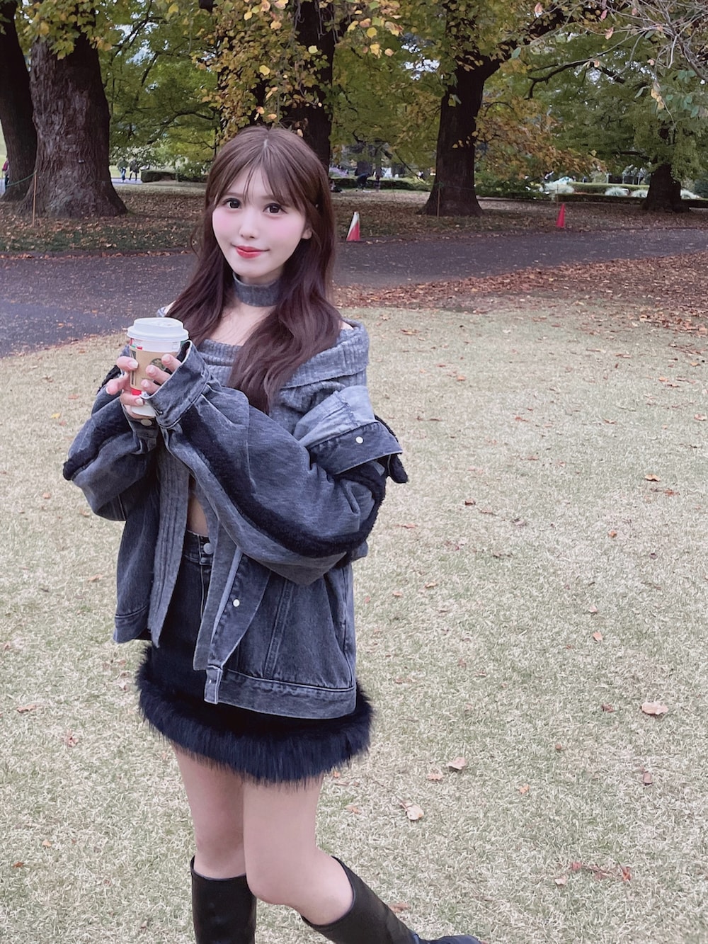 ブラック系のデニムジャケット、グレー系のニット/セーター、ブラック系のデニムスカートを着用したレディースの秋コーディネートの3枚目の写真