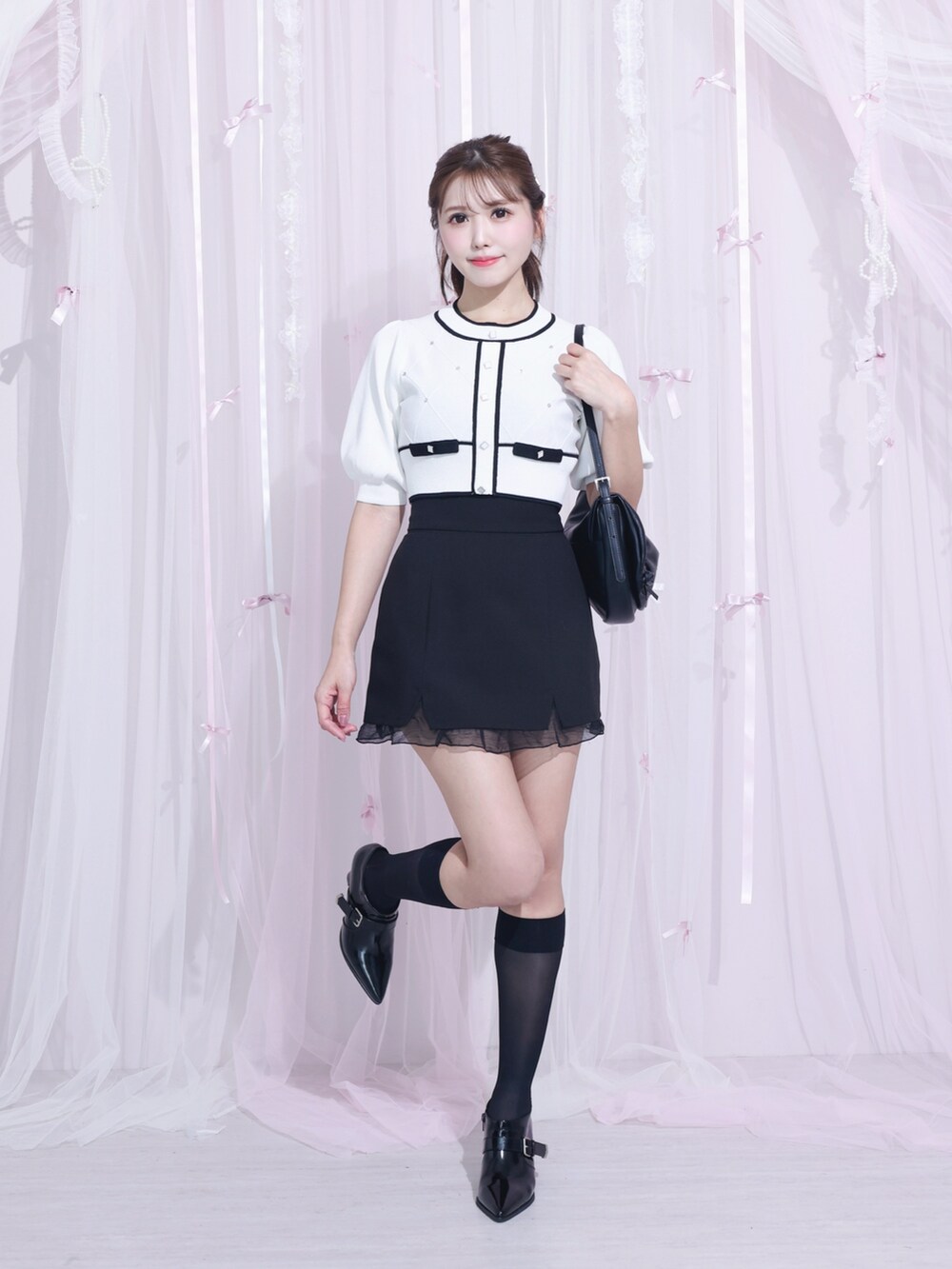 ブラック系のスカート、ホワイト系のニット/セーター、ブラック系のブーツを着用したレディースの冬コーディネートの2枚目の写真