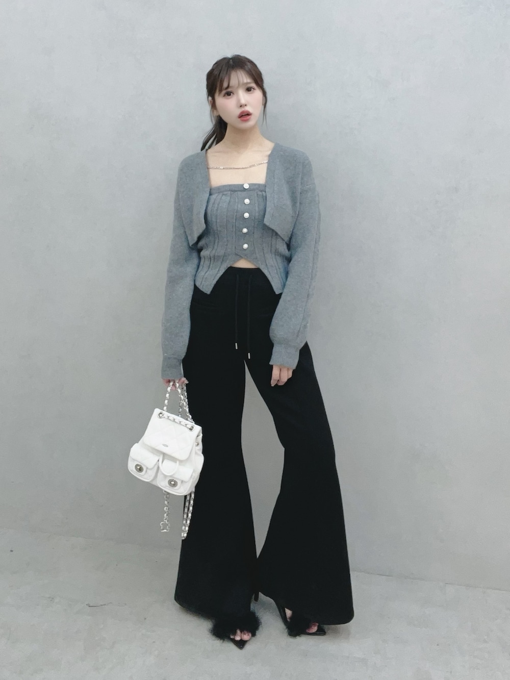 グレー系のニット/セーター、ブラック系のその他パンツ、ホワイト系のバックパック/リュックを着用したレディースの冬コーディネートの3枚目の写真