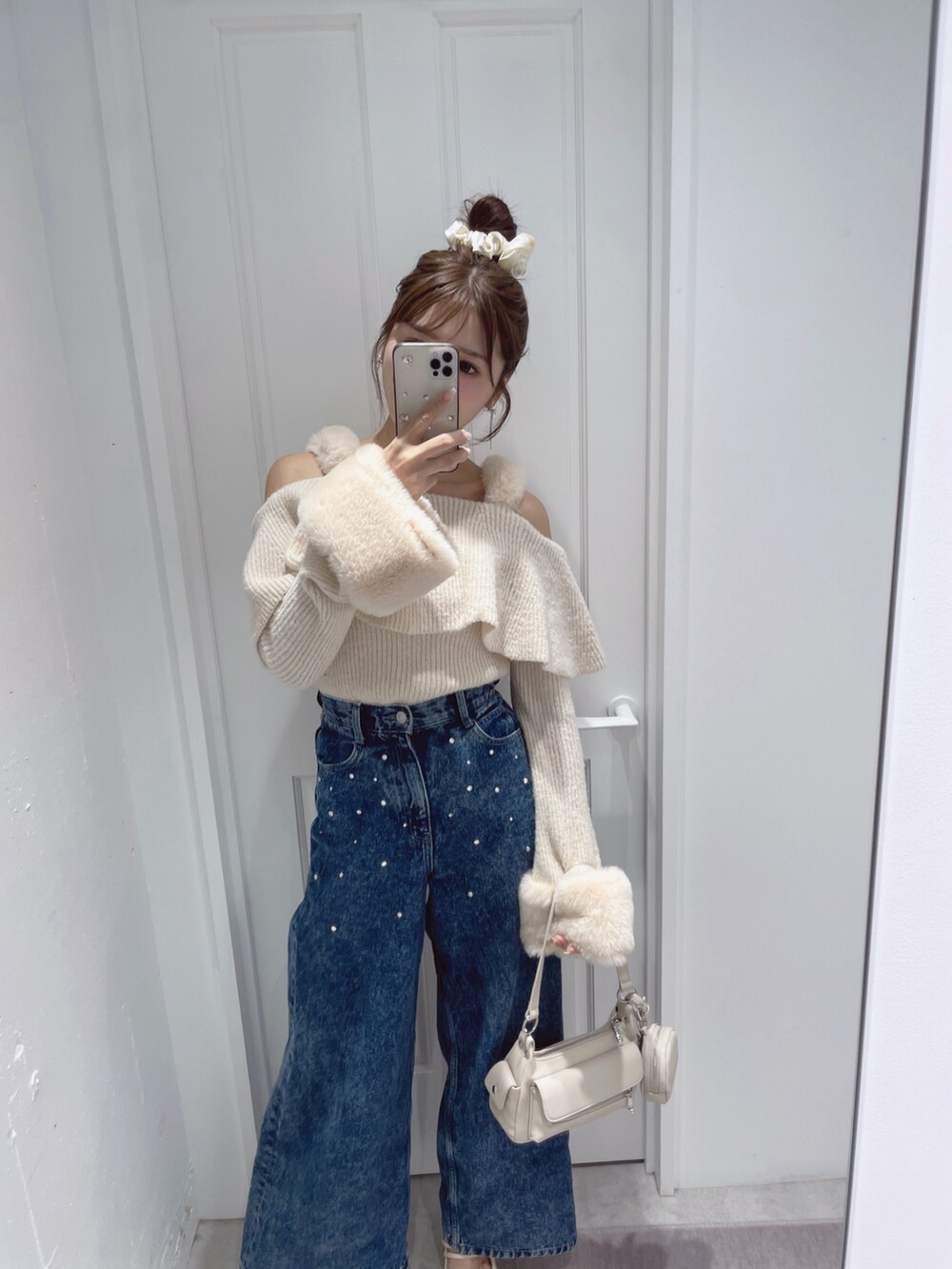 ホワイト系のニット/セーター、ブルー系のデニムパンツ、ホワイト系のパンプスを着用したレディースの秋コーディネートの5枚目の写真