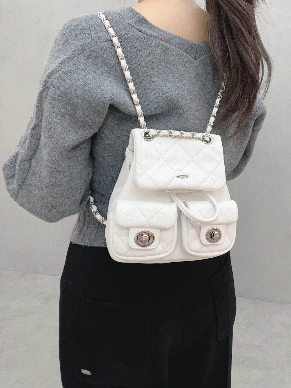 グレー系のニット/セーター、ブラック系のその他パンツ、ホワイト系のバックパック/リュックを着用したレディースの冬コーディネートの7枚目の写真