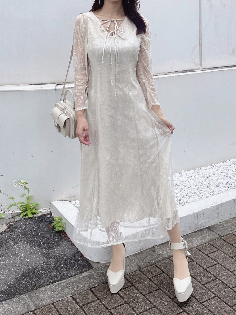 ホワイト系のパンプス、ホワイト系のハンドバッグ、ホワイト系のワンピースを着用したレディースの夏コーディネートの3枚目の写真