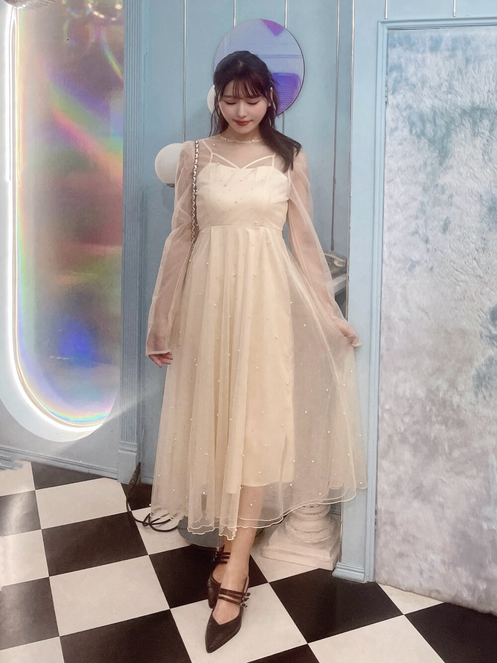 ホワイト系のワンピース、ブラック系のパンプス、ホワイト系のハンドバッグを着用したレディースの秋コーディネートの2枚目の写真