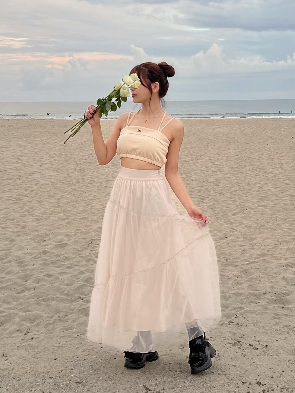 イエロー系のキャミソール、ベージュ系のスカートを着用したレディースの春コーディネートの3枚目の写真