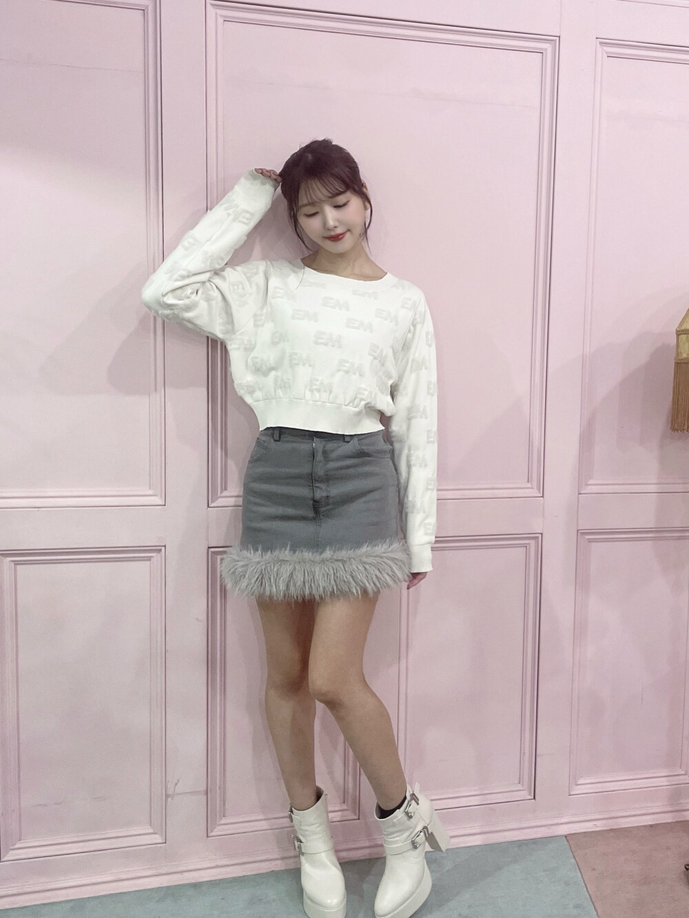 ホワイト系のニット/セーター、グレー系のデニムスカート、ホワイト系のブーツを着用したレディースの秋コーディネートの2枚目の写真