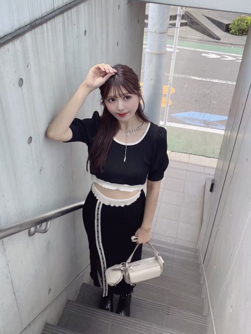 ブラック系のTシャツ/カットソー、ブラック系のスカート、ホワイト系のショルダーバッグを着用したレディースの秋コーディネートの2枚目の写真