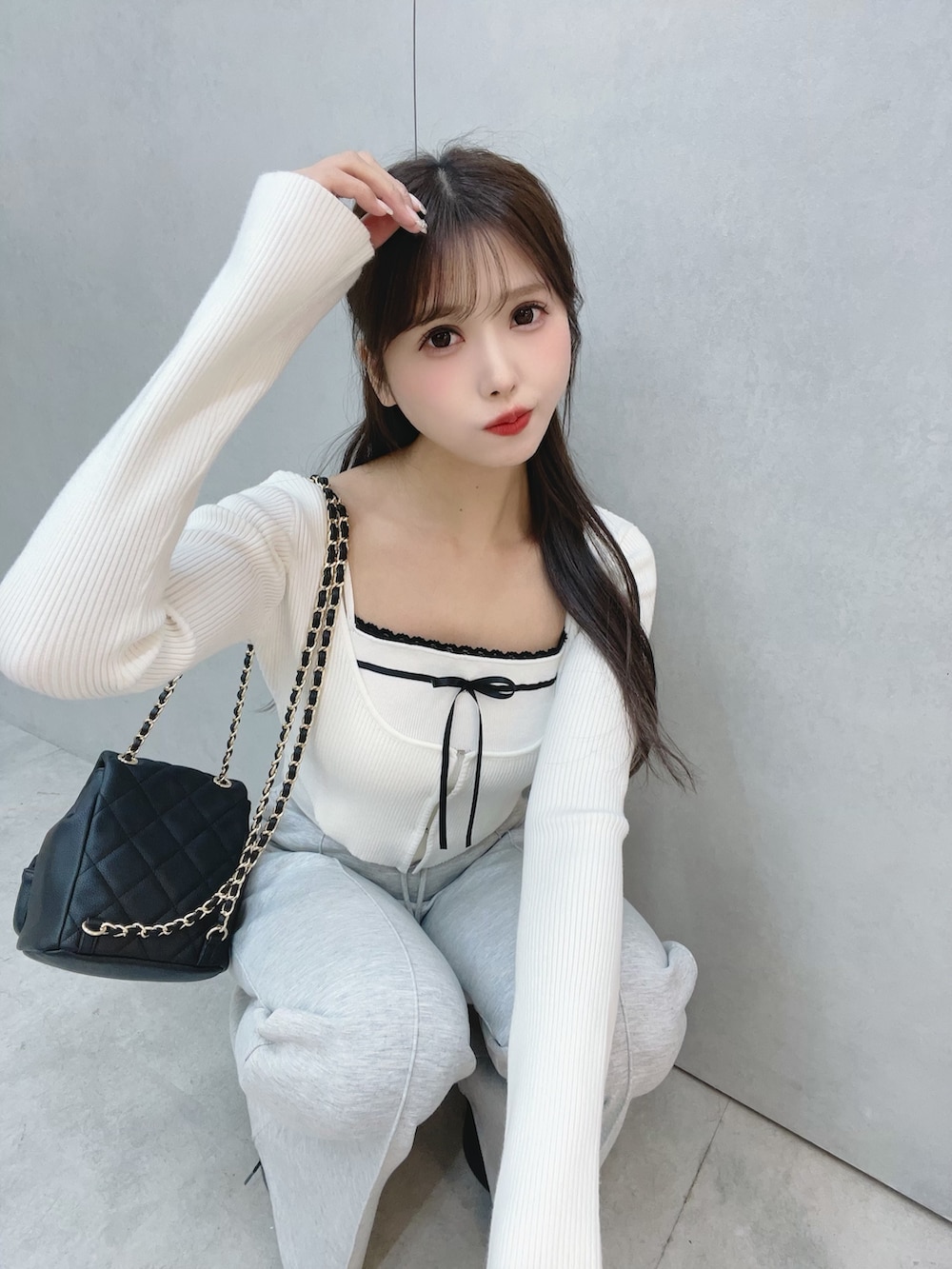 ホワイト系のニット/セーター、グレー系のその他パンツ、ブラック系のバックパック/リュックを着用したレディースの冬コーディネートの7枚目の写真