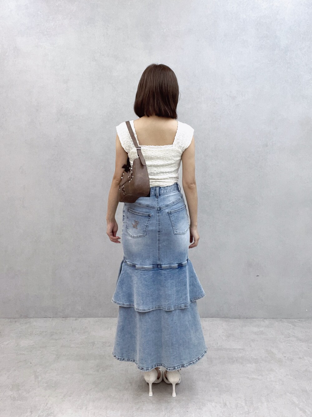 ブラウン系のショルダーバッグ、ホワイト系のTシャツ/カットソー、ブルー系のデニムスカートを着用したレディースの秋コーディネートの4枚目の写真