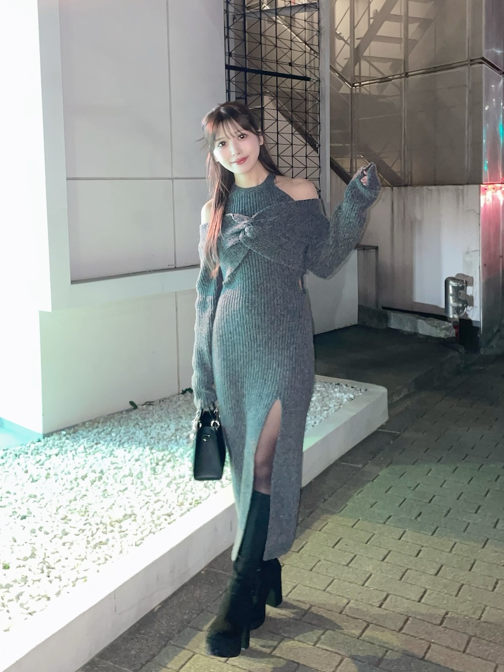 グレー系のワンピース、ブラック系のハンドバッグ、ブラック系のブーツを着用したレディースの冬コーディネートの3枚目の写真