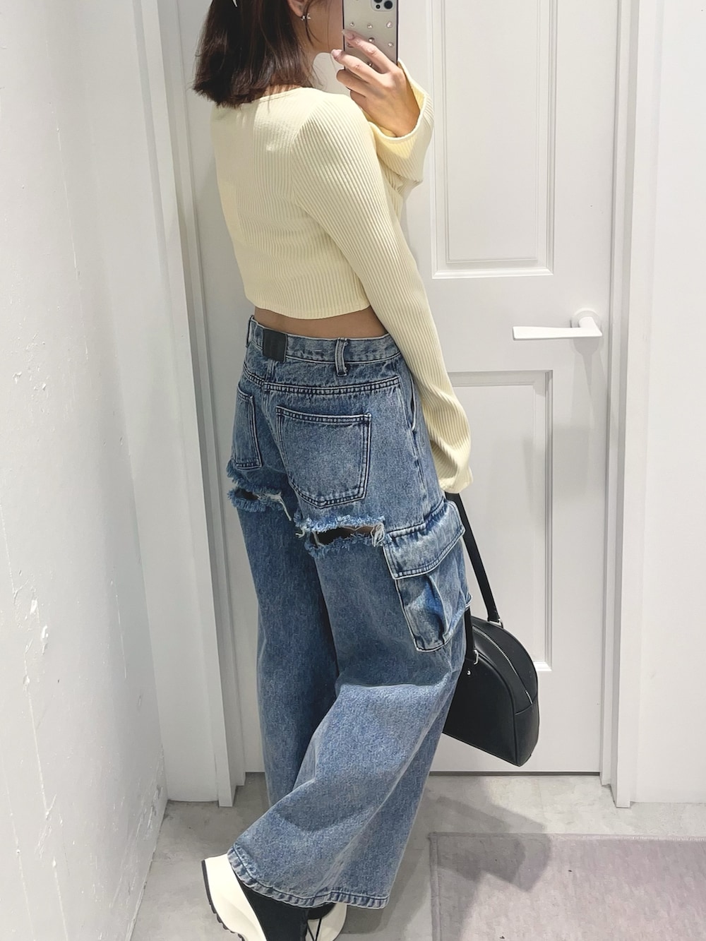 イエロー系のTシャツ/カットソー、ブルー系のデニムパンツ、ブラック系のボストンバッグを着用したレディースの冬コーディネートの6枚目の写真