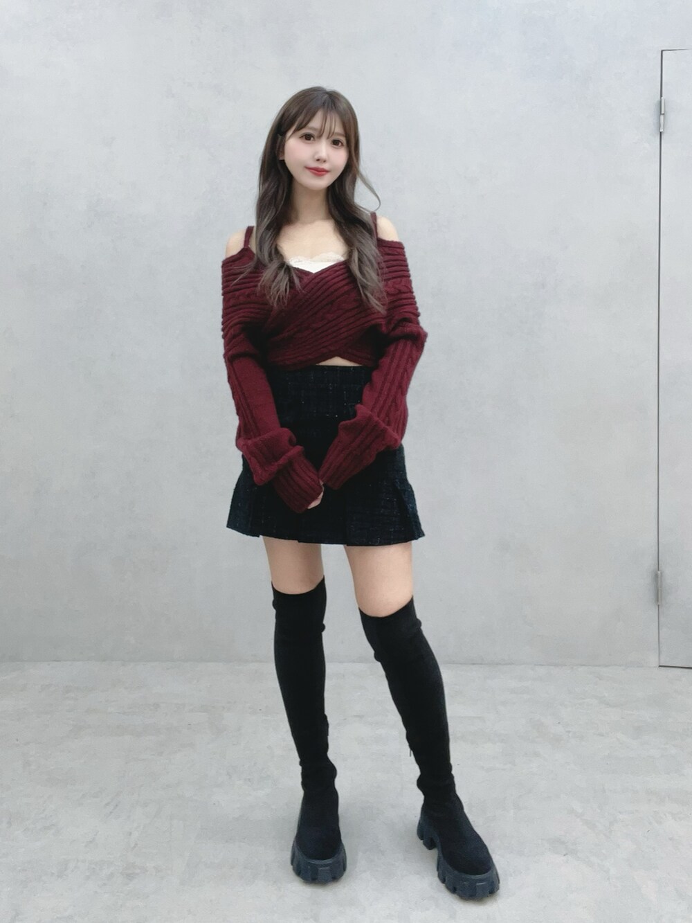 ブラック系のブーツ、ブラック系のスカート、レッド系のニット/セーターを着用したレディースの冬コーディネートの2枚目の写真