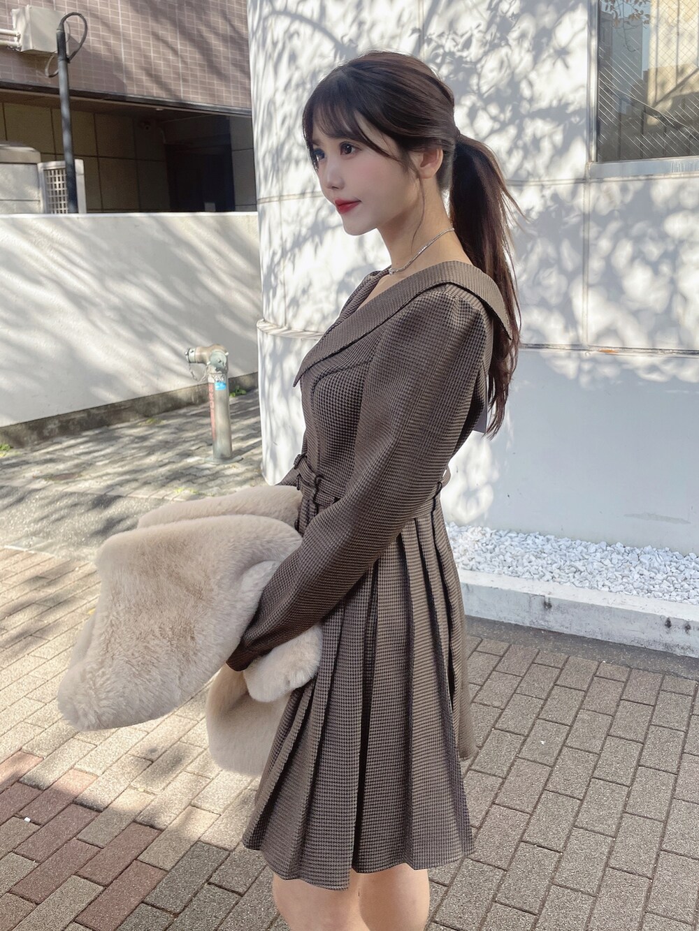 ブラウン系のワンピース、ベージュ系のその他アウター、ブラック系のローファーを着用したレディースの冬コーディネートの9枚目の写真