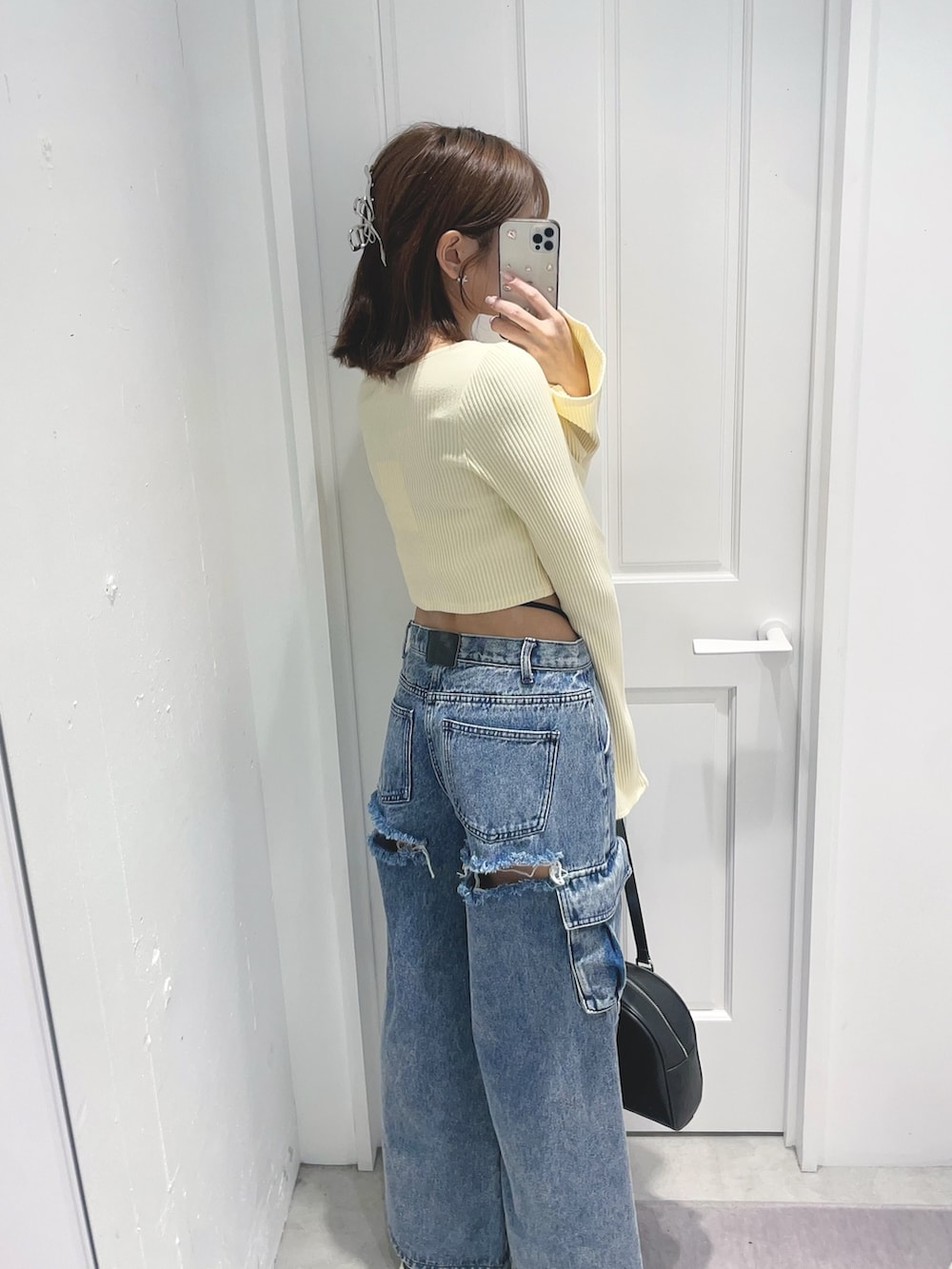 イエロー系のTシャツ/カットソー、ブルー系のデニムパンツ、ブラック系のボストンバッグを着用したレディースの冬コーディネートの5枚目の写真