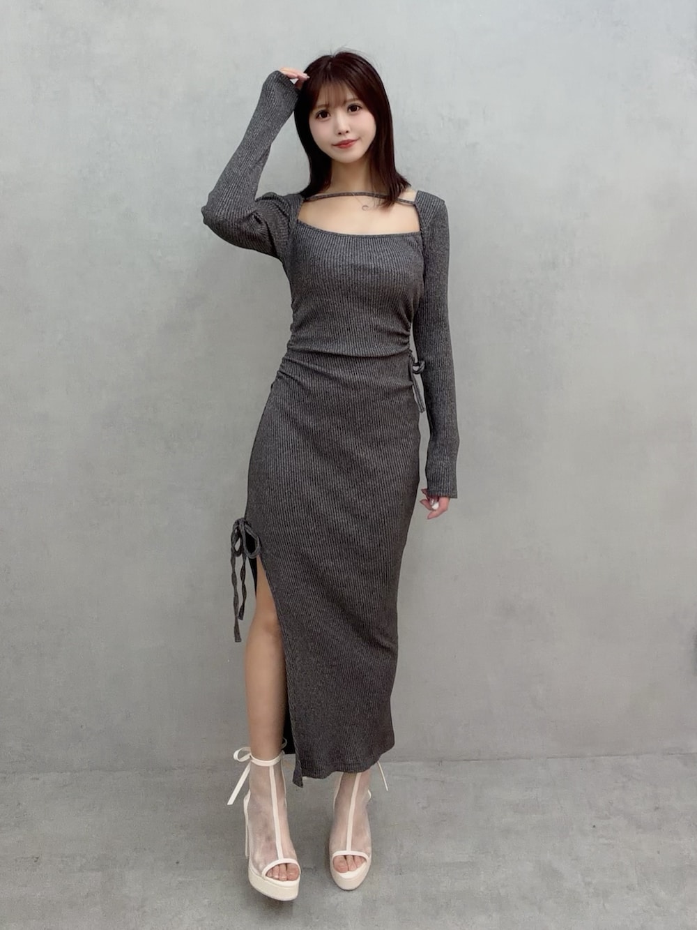 グレー系のワンピース、ホワイト系のサンダルを着用したレディースの冬コーディネートの2枚目の写真