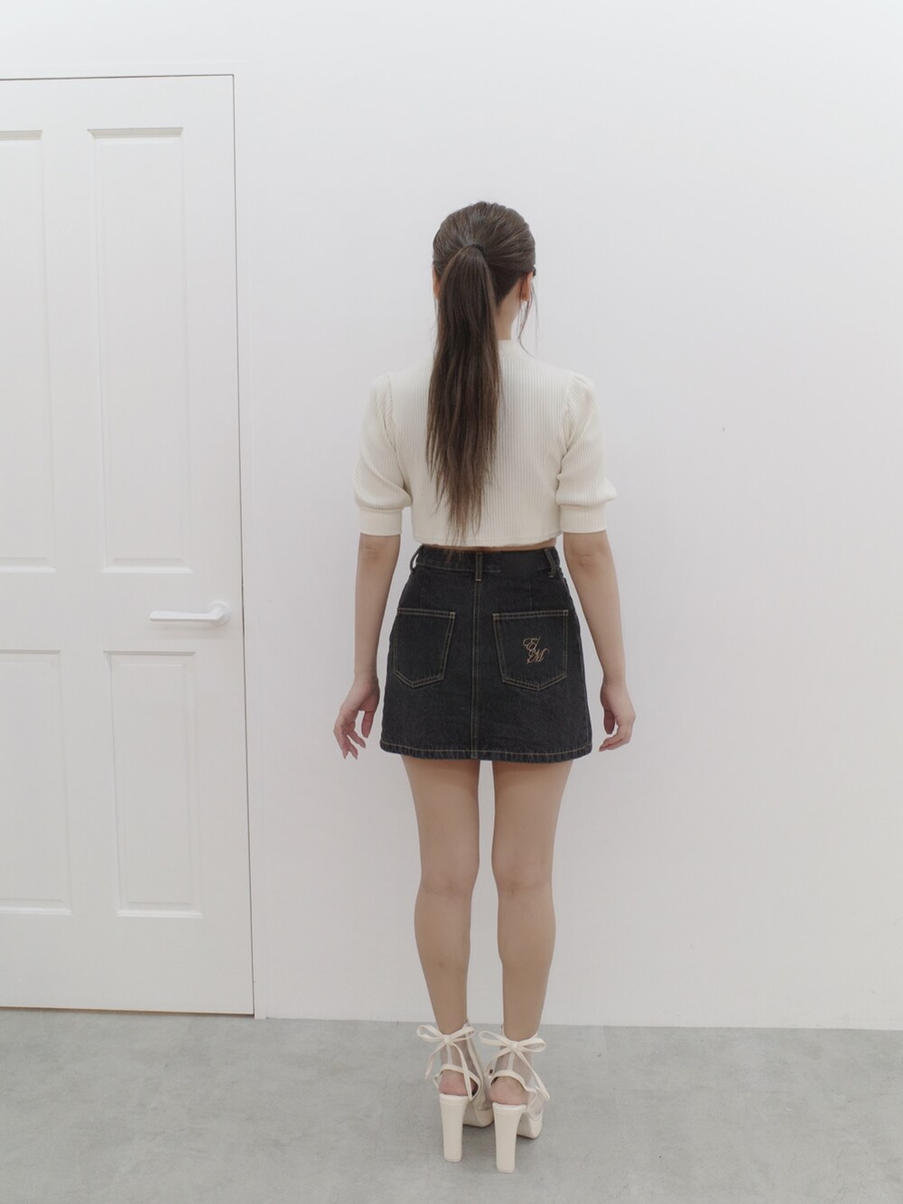 ブラック系のデニムスカート、ホワイト系のTシャツ/カットソーを着用したレディースの夏コーディネートの4枚目の写真