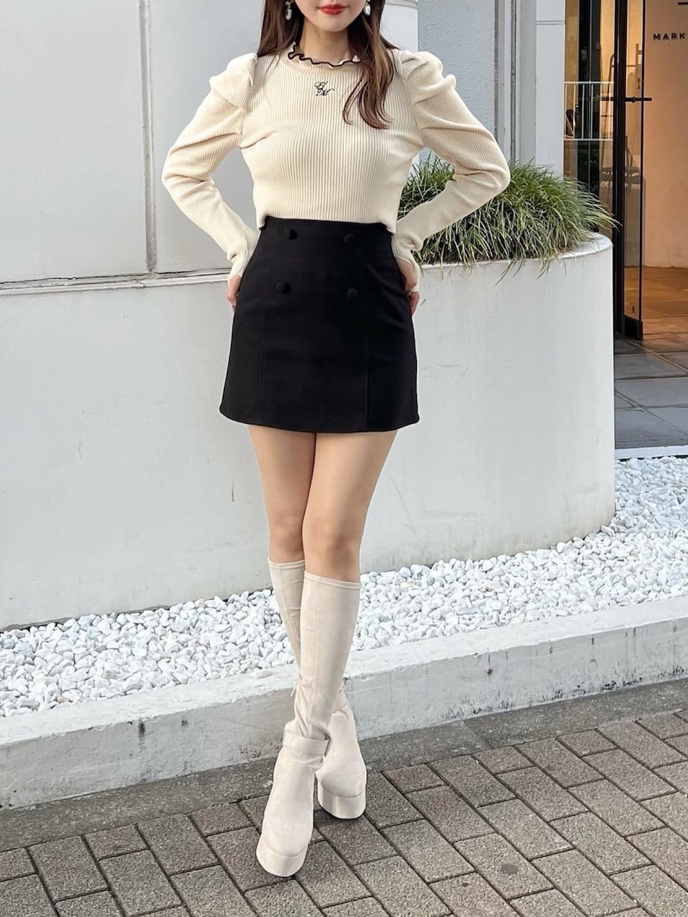 ホワイト系のニット/セーター、ブラック系のスカート、ホワイト系のブーツを着用したレディースの夏コーディネートの2枚目の写真
