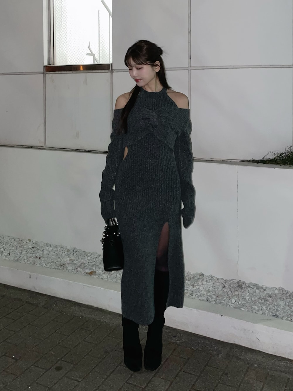 グレー系のワンピース、ブラック系のハンドバッグ、ブラック系のブーツを着用したレディースの冬コーディネートの4枚目の写真