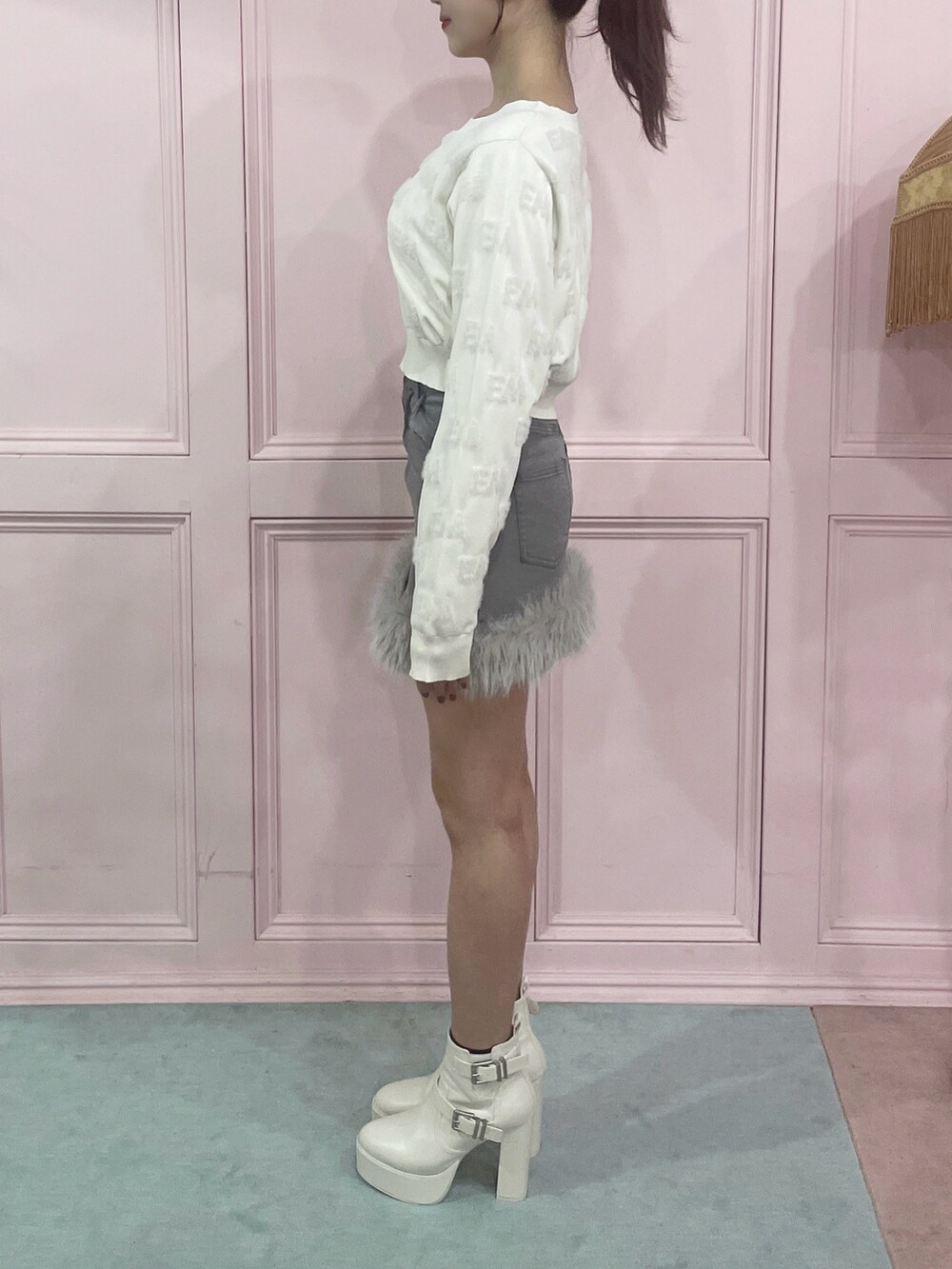 ホワイト系のニット/セーター、グレー系のデニムスカート、ホワイト系のブーツを着用したレディースの秋コーディネートの6枚目の写真