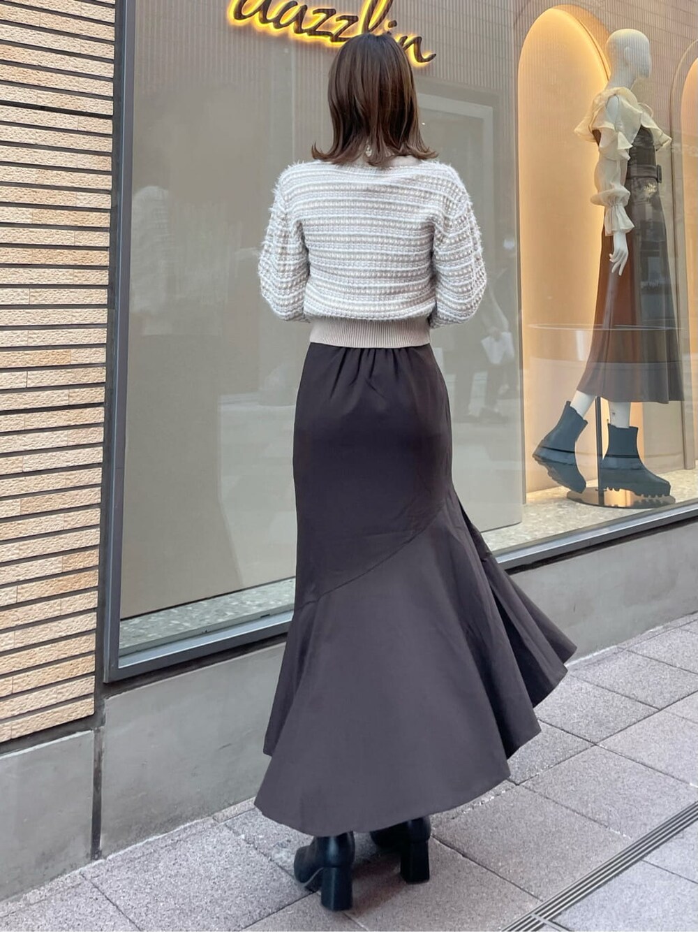 ブラウン系のスカート、ブラック系のブーツ、ベージュ系のカーディガン/ボレロを着用したレディースの秋コーディネートの3枚目の写真