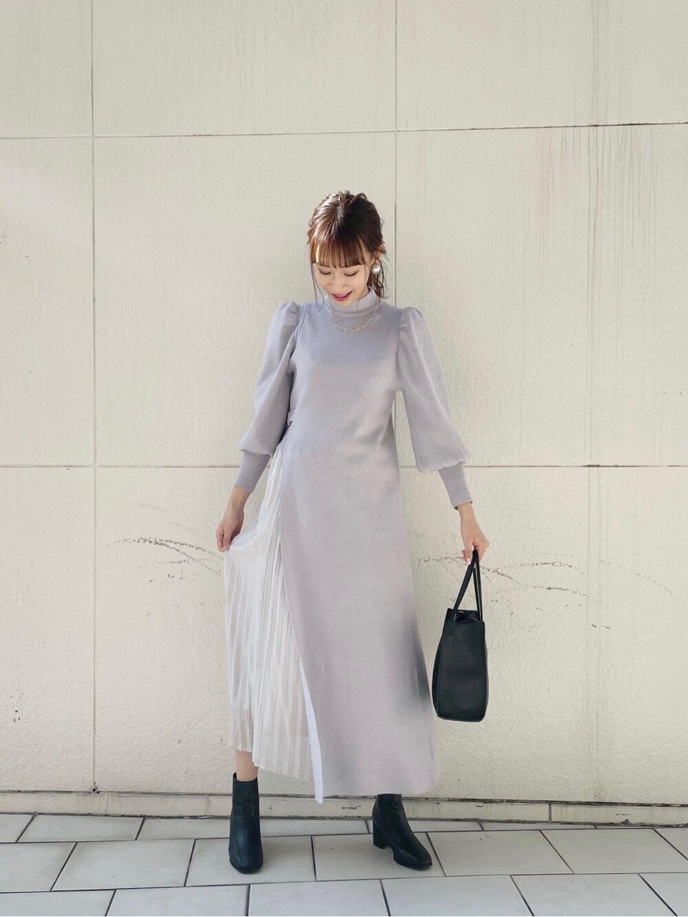 ブラック系のブーツ、ブラック系のハンドバッグ、グレー系のワンピースを着用したレディースの冬コーディネートの2枚目の写真