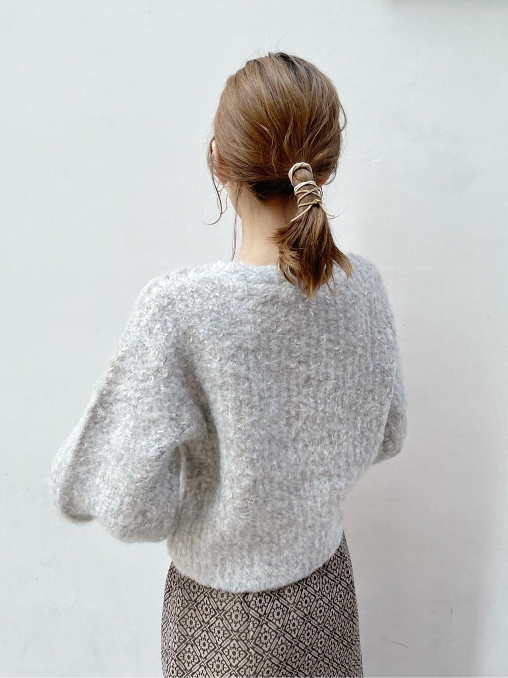 ブラック系のブーツ、ベージュ系のニット/セーター、ゴールド系のスカートを着用したレディースの秋コーディネートの6枚目の写真