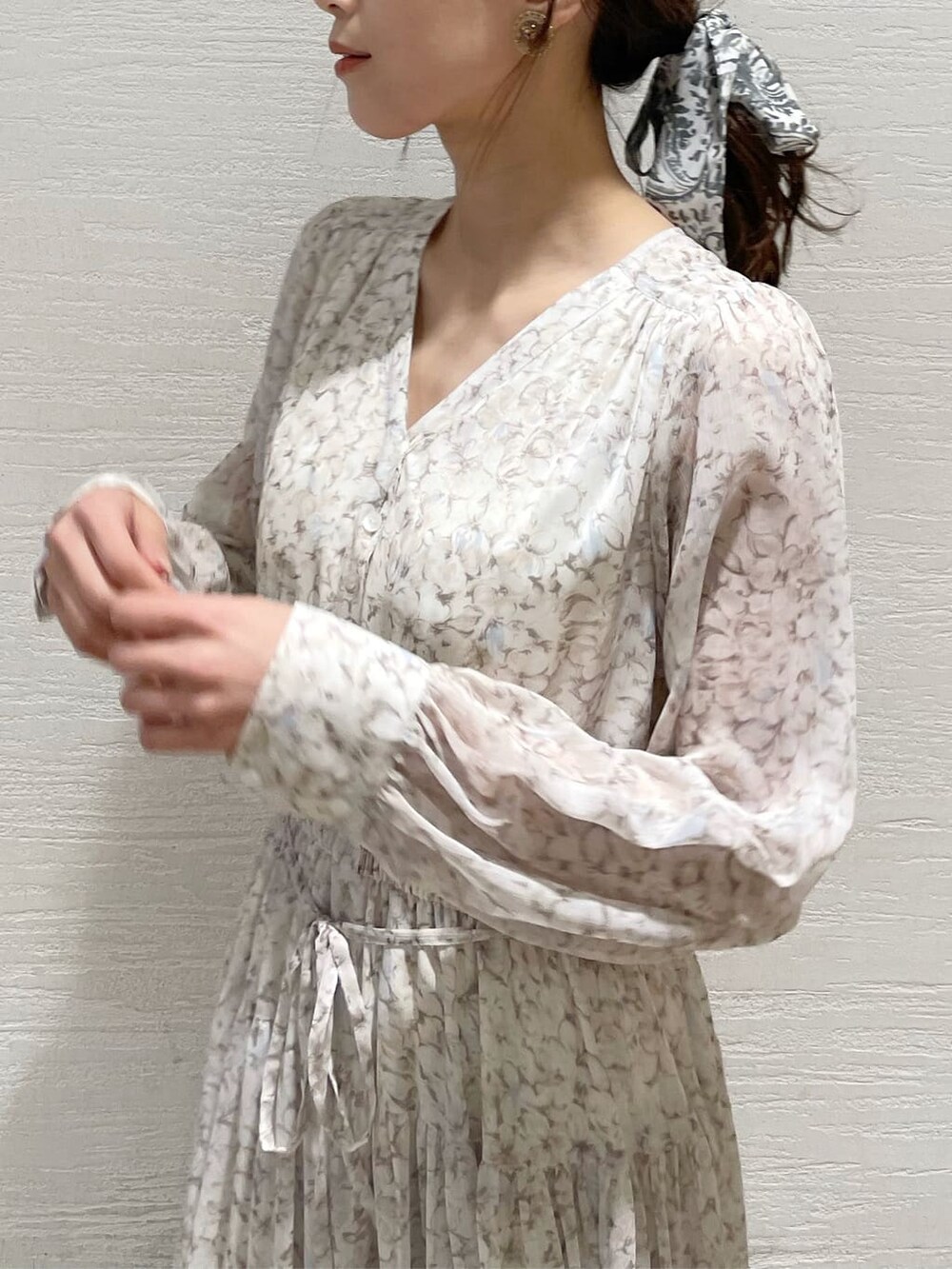 グレー系のトレンチコート、オレンジ系のワンピース、グレー系のニット/セーターを着用したレディースの冬コーディネートの9枚目の写真