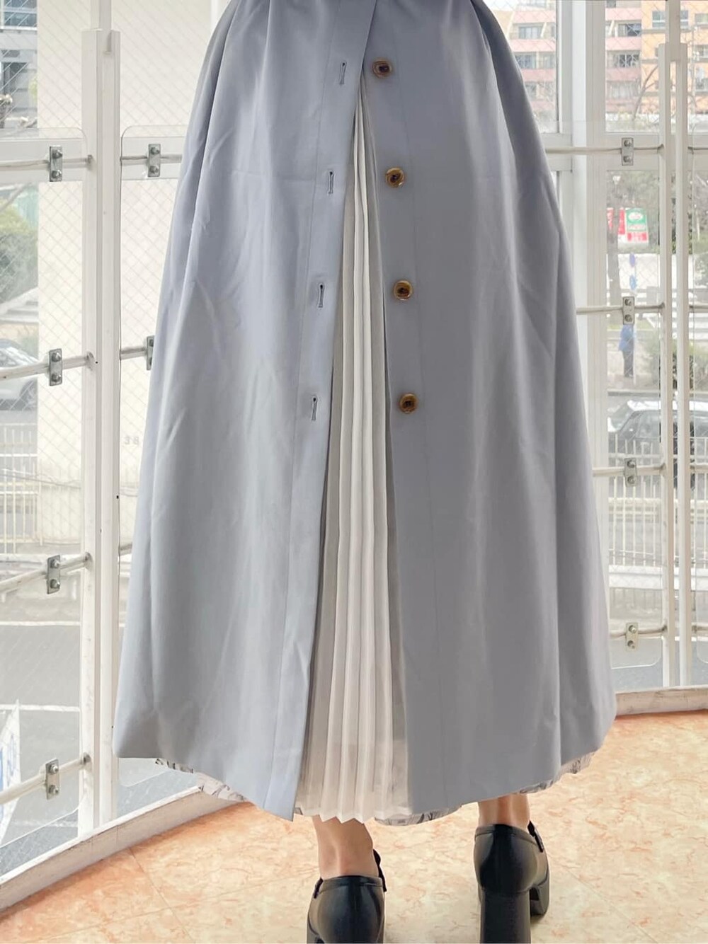 ブルー系のトレンチコート、グレー系のワンピース、ブラック系のローファーを着用したレディースの冬コーディネートの8枚目の写真