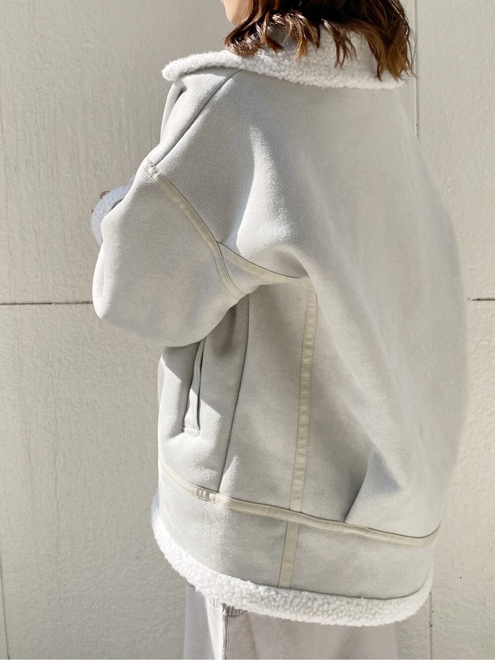 グレー系のブルゾン、ブラック系のブーツ、グレー系のワンピースを着用したレディースの秋コーディネートの4枚目の写真