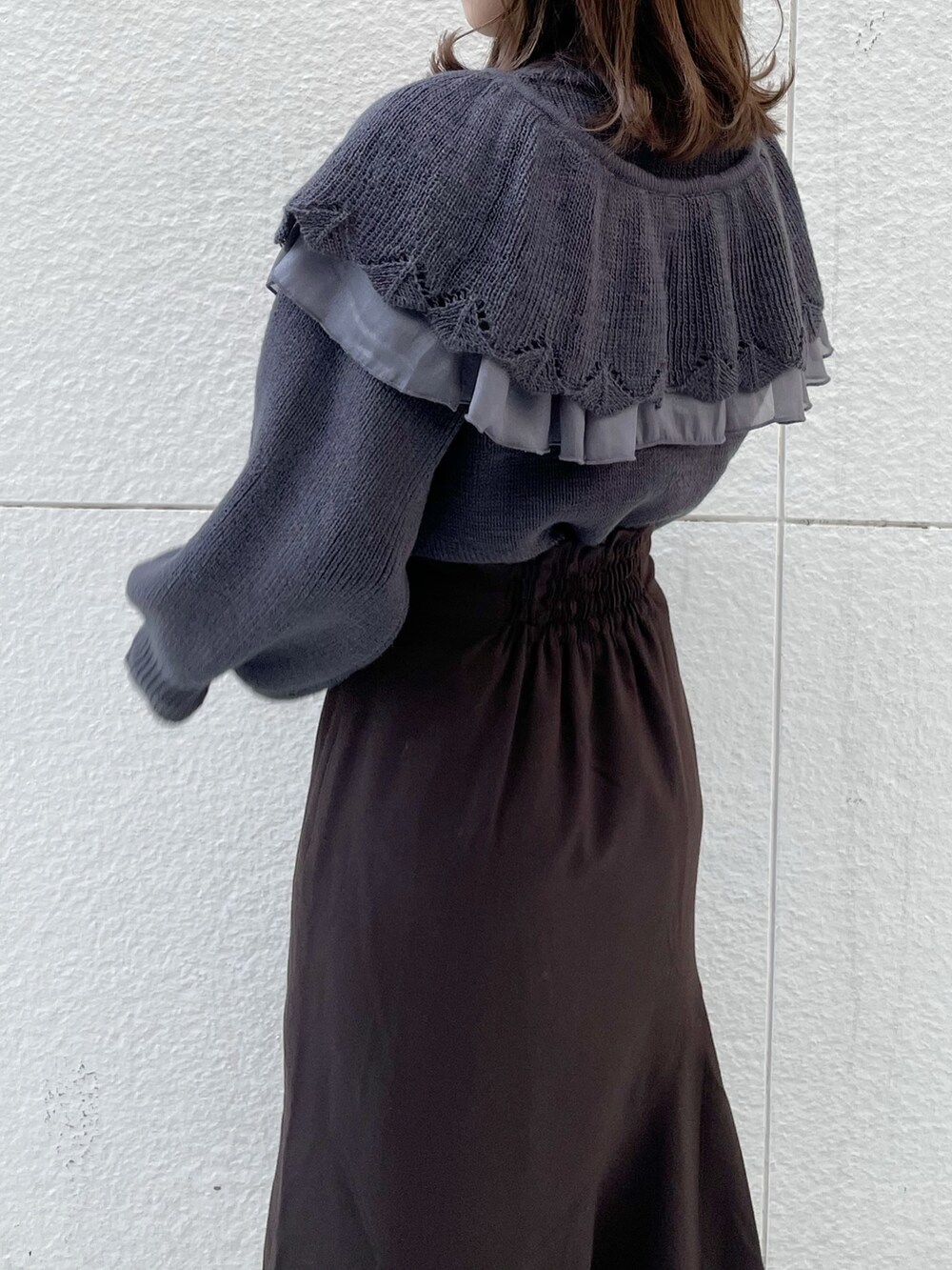 グレー系のニット/セーター、ブラウン系のスカート、ブラック系のブーツを着用したレディースの冬コーディネートの5枚目の写真