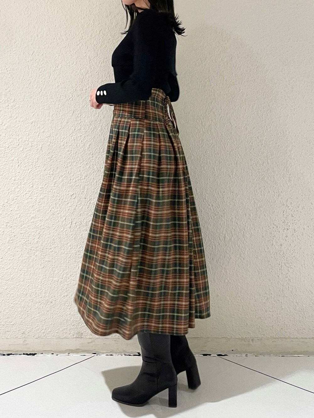 ブラック系のニット/セーター、ブラック系のブーツ、グリーン系のスカートを着用したレディースの秋コーディネートの4枚目の写真