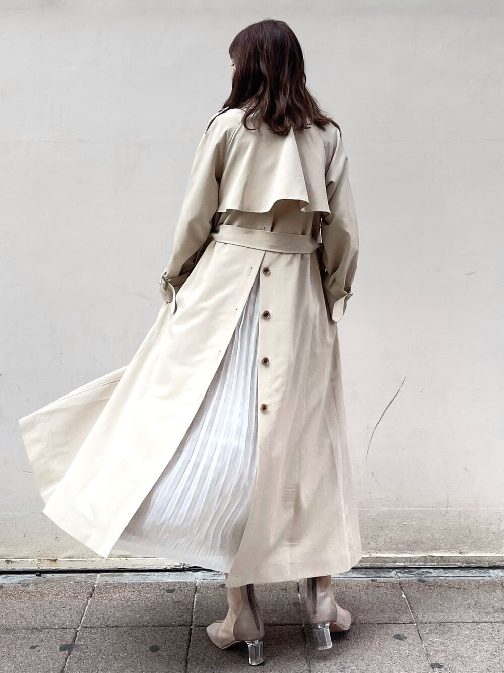 ベージュ系のトレンチコート、ホワイト系のワンピース、ベージュ系のブーツを着用したレディースの春コーディネートの2枚目の写真