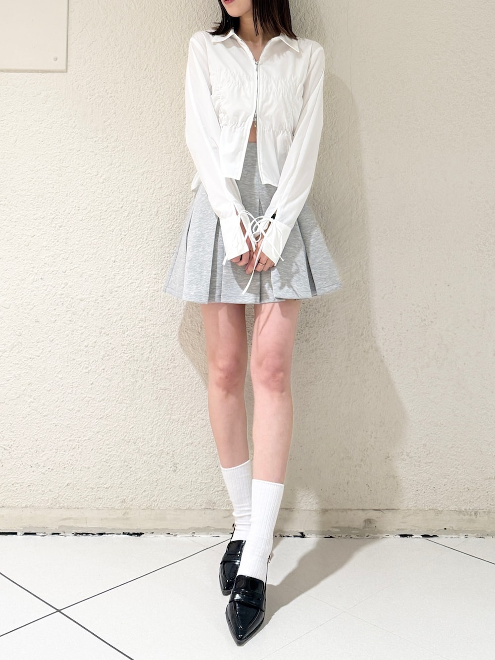 グレー系のスカート、ブラック系のハンドバッグ、ホワイト系のシャツ/ブラウスを着用したレディースの春コーディネートの2枚目の写真