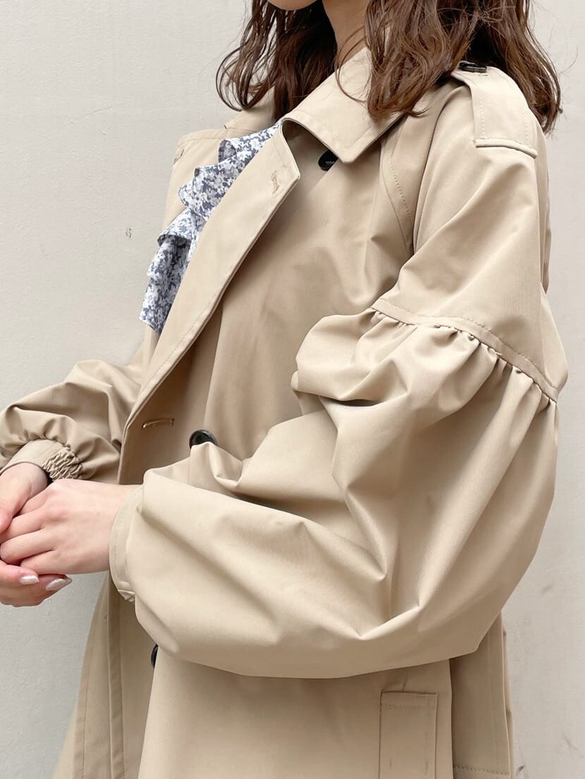 ベージュ系のトレンチコート、ブルー系のワンピース、ブラック系のブーツを着用したレディースの冬コーディネートの6枚目の写真