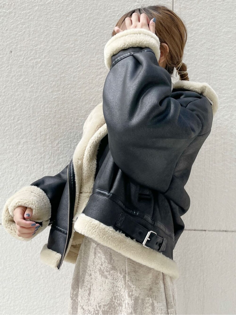 ブラック系のブルゾン、ベージュ系のスカート、ブラック系のブーツを着用したレディースの秋コーディネートの4枚目の写真