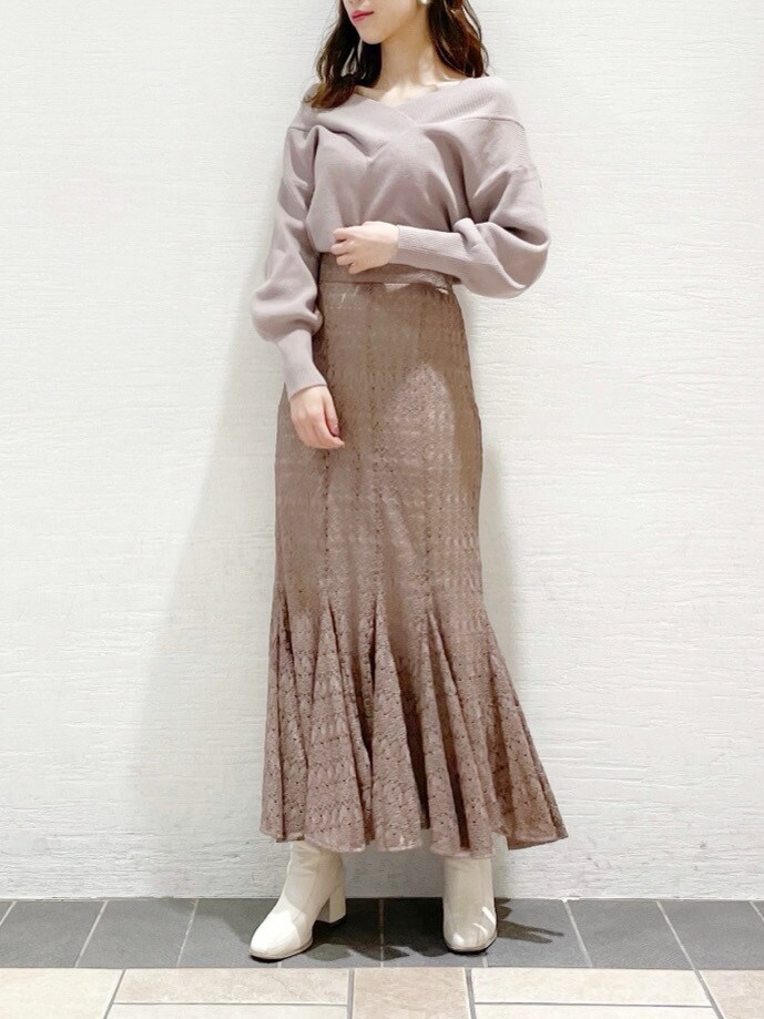 ホワイト系のブーツ、ベージュ系のスカート、パープル系のニット/セーターを着用したレディースの冬コーディネートの2枚目の写真