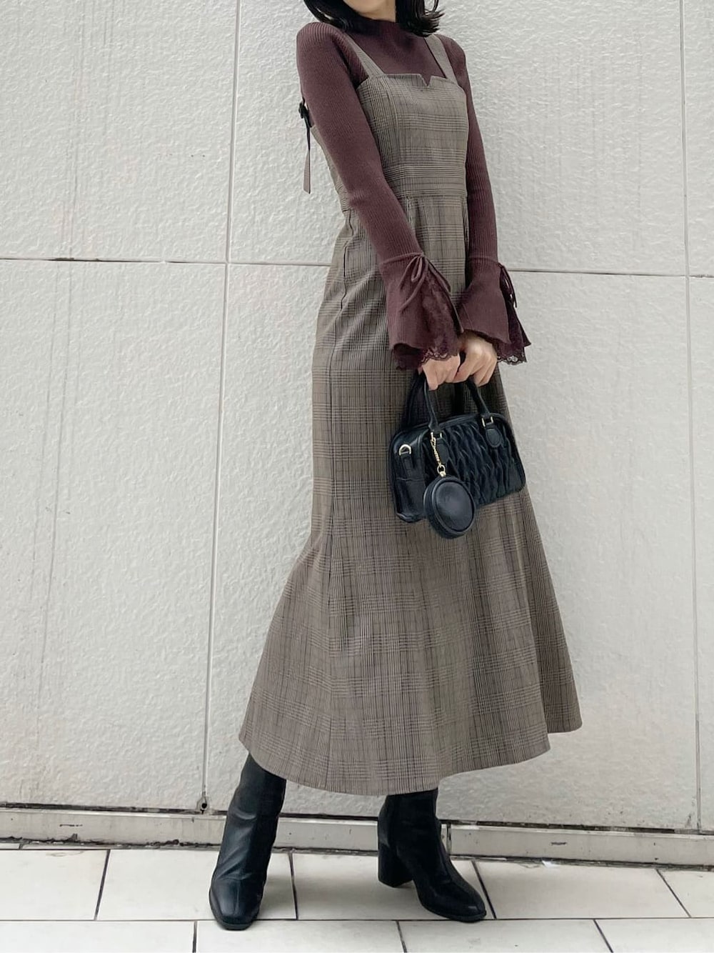 ベージュ系のライダースジャケット、ブラック系のブーツ、その他のジャンパースカートを着用したレディースの秋コーディネートの2枚目の写真