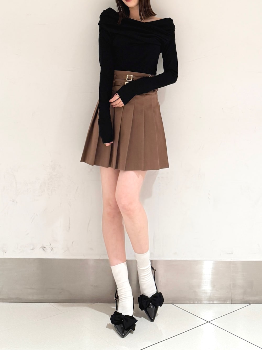 ブラック系のTシャツ/カットソー、ブラック系のパンプス、ブラウン系のスカートを着用したレディースの春コーディネートの2枚目の写真