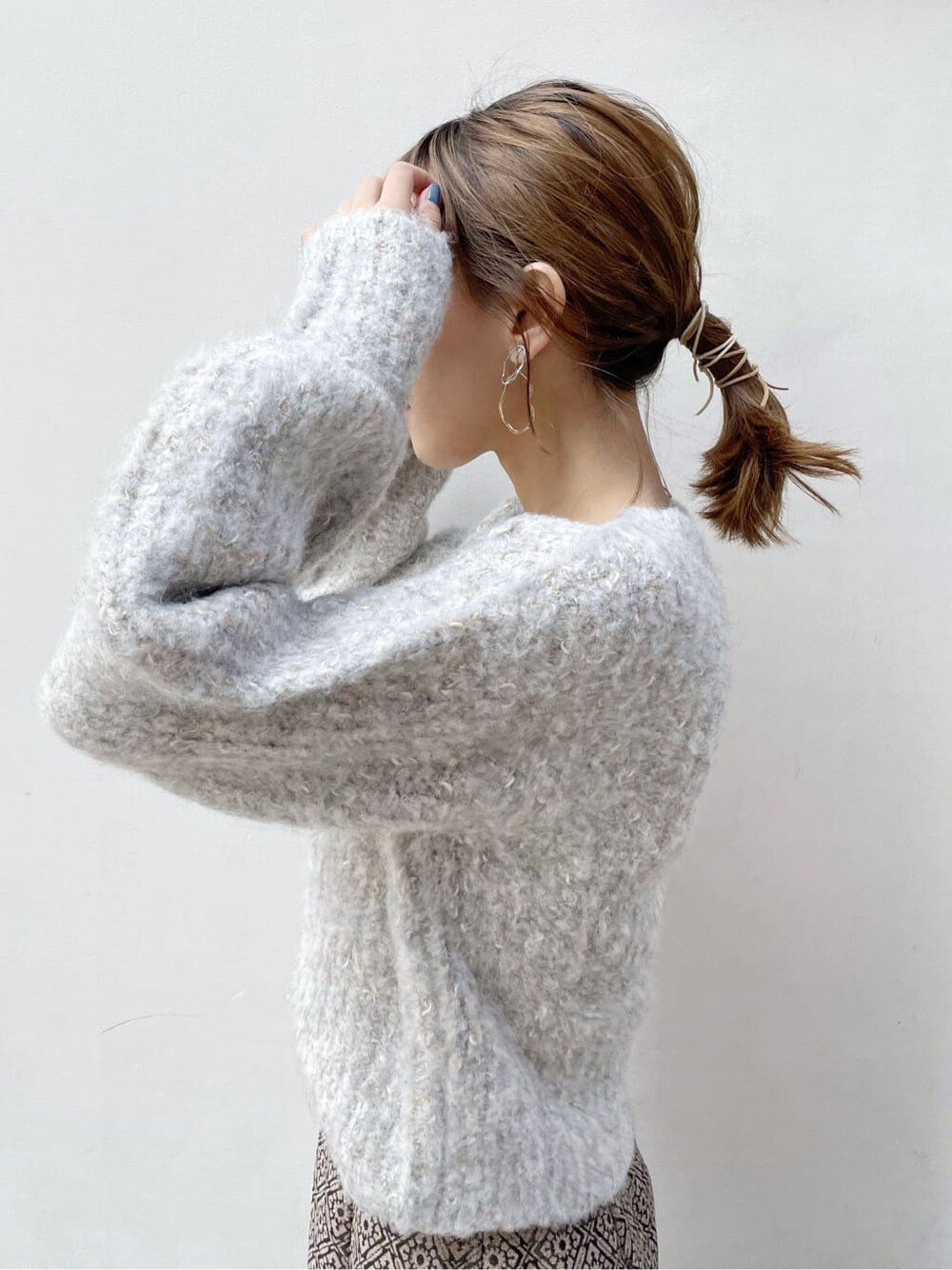 ブラック系のブーツ、ベージュ系のニット/セーター、ゴールド系のスカートを着用したレディースの秋コーディネートの5枚目の写真