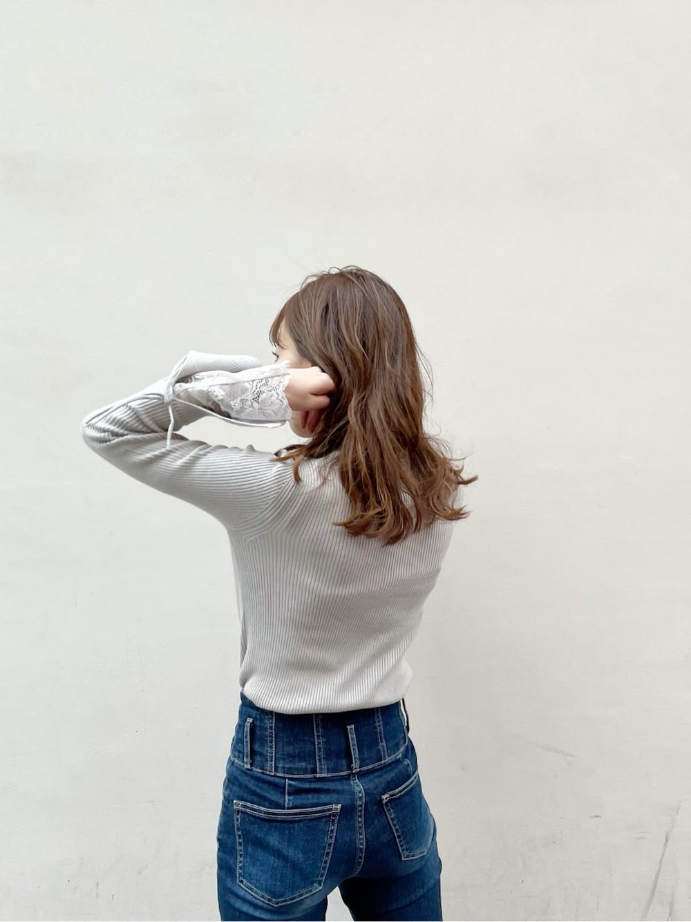 ブルー系のデニムパンツ、ブラック系のブーツ、グレー系のニット/セーターを着用したレディースの冬コーディネートの2枚目の写真