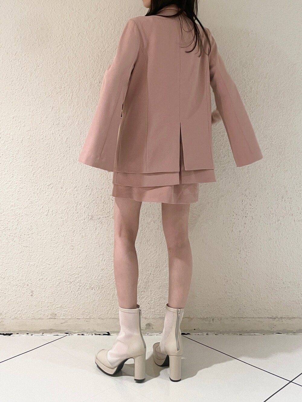 ピンク系のテーラードジャケット、ピンク系のスカート、ホワイト系のブーツを着用したレディースの冬コーディネートの4枚目の写真