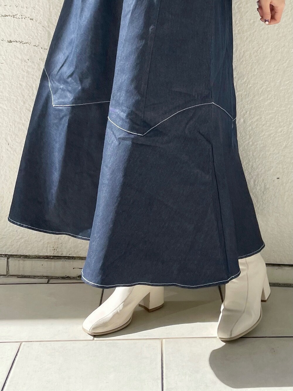 ホワイト系のブーツ、ブラック系のニット/セーター、ブルー系のワンピースを着用したレディースの冬コーディネートの10枚目の写真