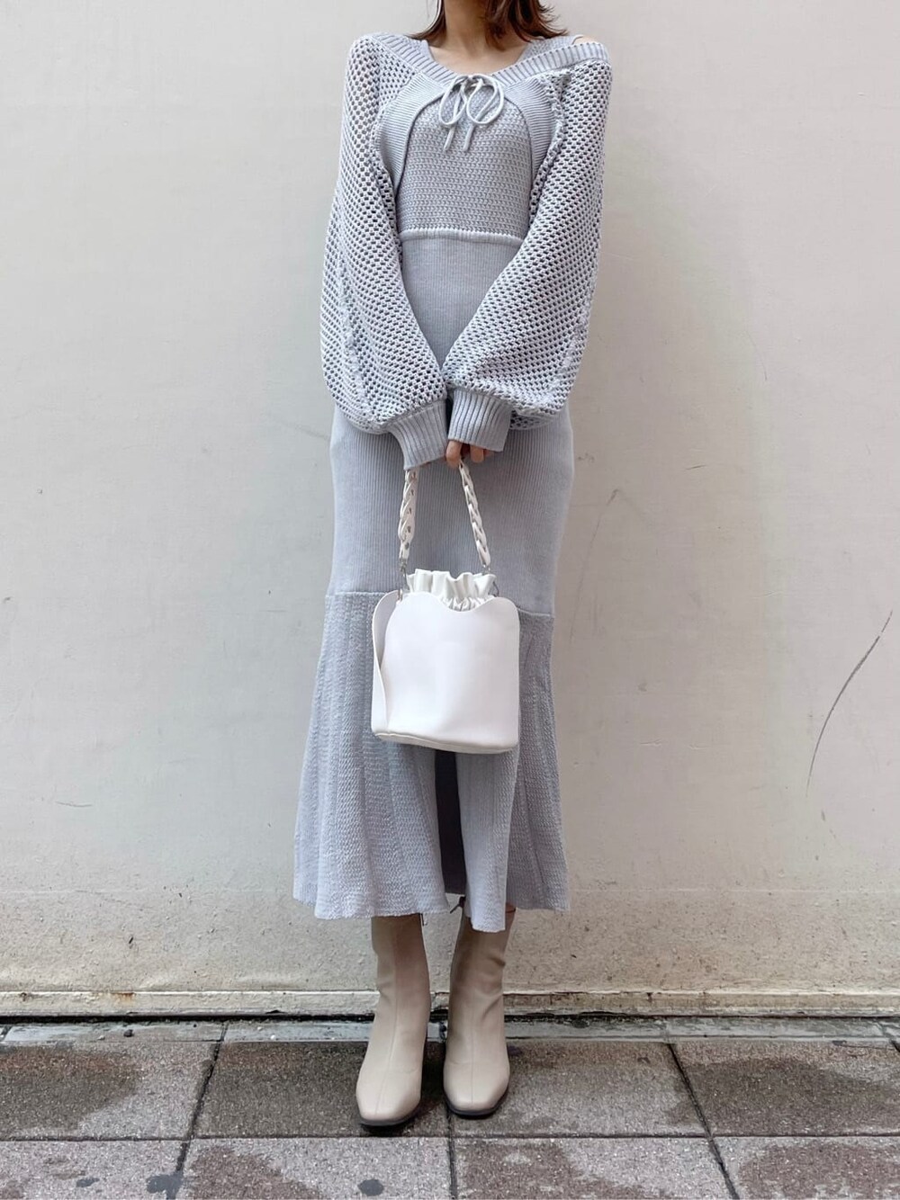 グレー系のワンピース、ホワイト系のハンドバッグ、ベージュ系のブーツを着用したレディースの秋コーディネートの4枚目の写真