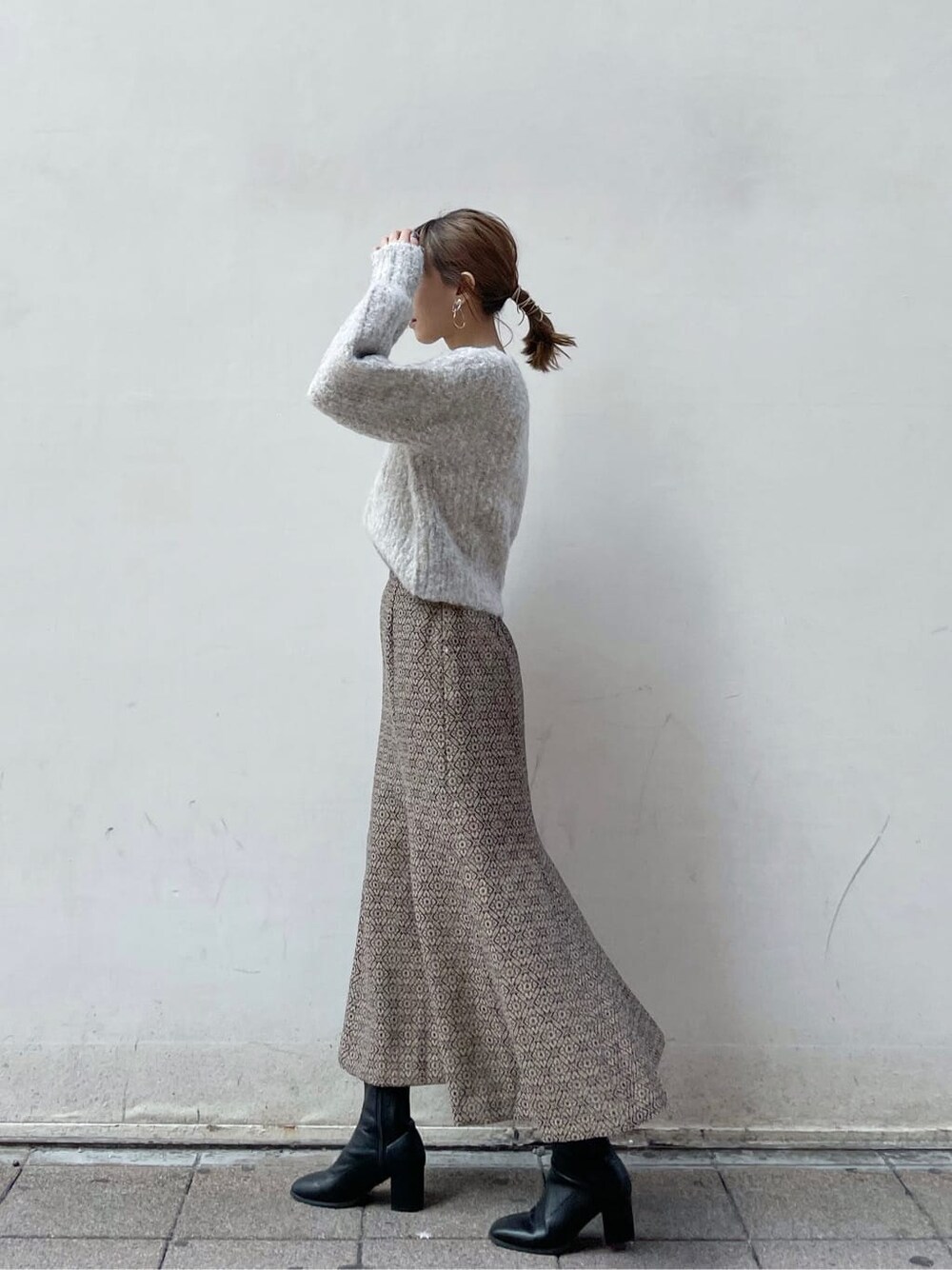 ブラック系のブーツ、ベージュ系のニット/セーター、ゴールド系のスカートを着用したレディースの秋コーディネートの2枚目の写真