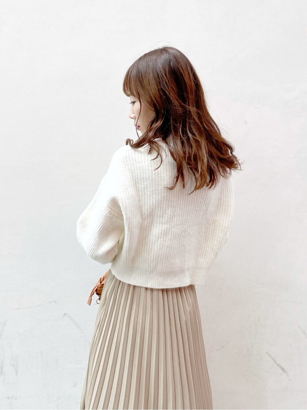 ブラウン系のクラッチバッグ、ホワイト系のニット/セーター、ブラウン系のブーツを着用したレディースの冬コーディネートの6枚目の写真